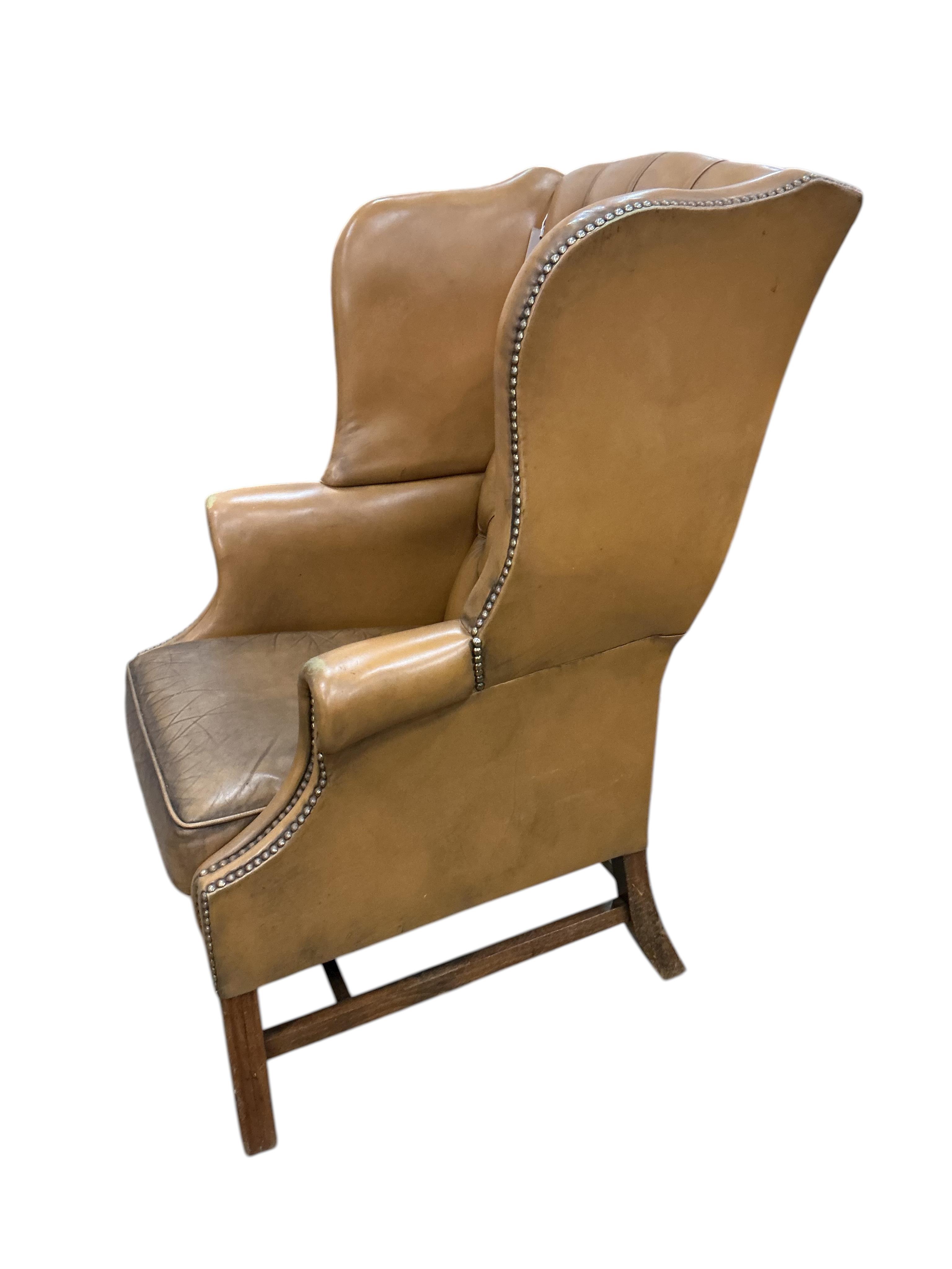 A George III style buttoned tan leather wing armchair, width 74cm, depth 74cm, depth 64cm, height 108cm